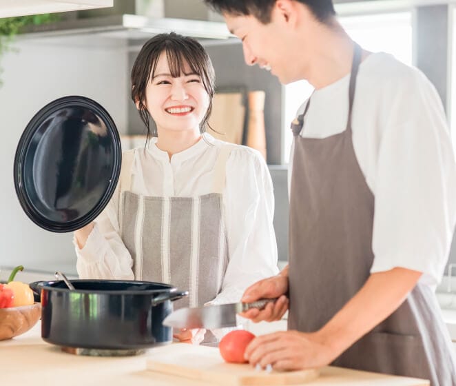 男性と女性が笑顔でキッチンで料理をしている